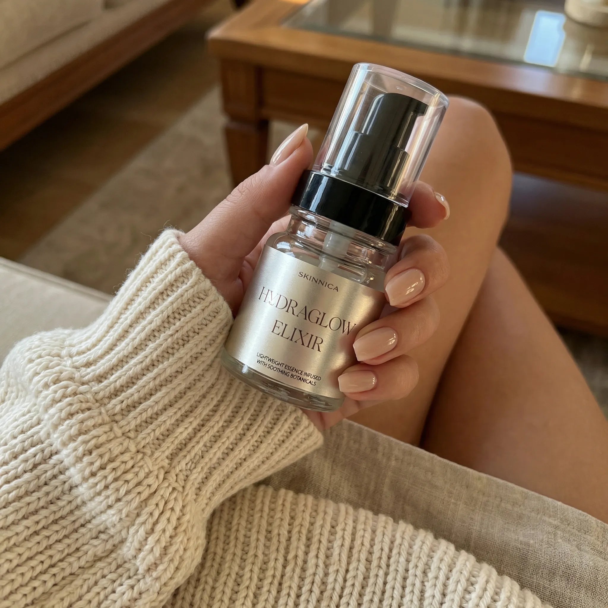Hand holding the HYDRAGLOW ELIXIR 80ml serum bottle showing size and form